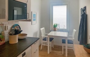 Compact kitchen with microwave, sink, and countertop, featuring a dining table and chairs.