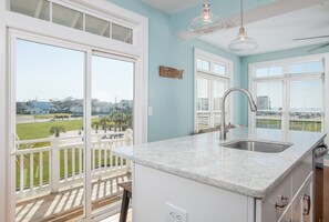 A kitchen with a large window, a balcony, and a view of the beach.