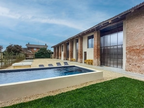 A modern house with a swimming pool, a patio with chairs, and a large window. - Wonderful private villa for 14 people with WIFI, A/C, private pool, hot tub, TV and patio (Poirino)