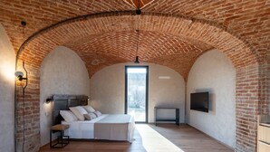 A bedroom with a brick ceiling, a bed, a desk, and a TV. - Beautiful private villa for 14 guests with private pool, WIFI, hot tub, A/C, TV and patio (Poirino)