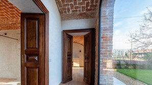 A hallway with wooden doors and a view of a brick wall and greenery outside. - Beautiful private villa for 14 guests with private pool, WIFI, hot tub, A/C, TV and patio (Poirino)