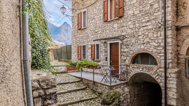 A stone building with wooden shutters, a small outdoor seating area, and a view of mountains in the background. - Wonderful private villa for 6 guests with WIFI, TV, terrace and pets allowed (San Mamete)