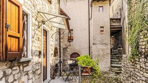 A narrow stone alley with a wooden door, a metal chair, a table, and a potted plant. - Wonderful private villa for 6 guests with WIFI, TV, terrace and pets allowed (San Mamete)