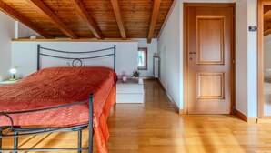 A bedroom with a wooden ceiling, a bed with a red blanket, a bedside table with a lamp, and a door leading to another room. - Wonderful private villa for 6 guests with WIFI, TV, terrace and pets allowed (San Mamete)