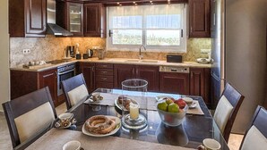 Una cocina moderna con armarios de madera oscura, un refrigerador de acero inoxidable y una mesa de comedor preparada para cuatro.