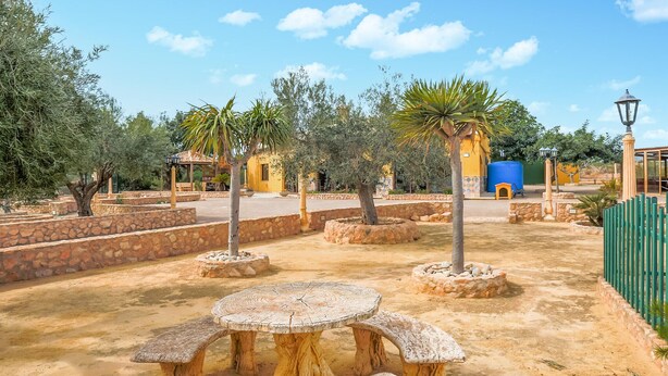 A courtyard with stone walls, a round wooden table, and benches. - Beautiful home in Pozo de los Palos (Pozo de los Palos)