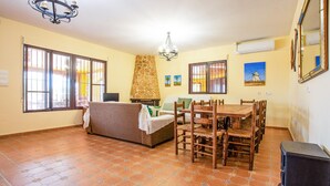 A living room with a sofa, dining table, chairs, a fireplace, and a chandelier. - Beautiful home in Pozo de los Palos (Pozo de los Palos)