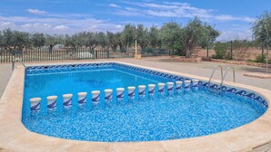 A rectangular swimming pool with a blue mosaic tile border, surrounded by a stone deck and a metal fence. - Beautiful home in Pozo de los Palos (Pozo de los Palos)