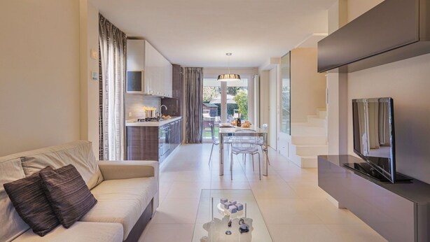 A modern apartment with a living room, dining area, kitchenette, and a balcony.