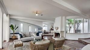 A spacious living area with a fireplace, comfortable seating, and large windows offering views of the outdoors. - Wonderful private villa for 10 guests with private pool, A/C, hot tub, WIFI, TV and patio (Praia Maria Luisa)