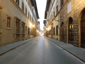 Una calle estrecha flanqueada por edificios históricos, con ventanas de arco y fachadas de piedra.