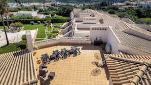 A rooftop terrace with outdoor seating, a pool, and a view of the sea and surrounding buildings.