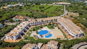 An aerial view of a resort with multiple buildings, a central pool area, and surrounding greenery.