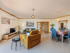 A modern living room with a sofa, TV, and dining area.