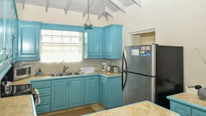 A kitchen with turquoise cabinets, a stainless steel refrigerator, and a microwave.