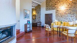 Una habitación acogedora con pared de piedra, techo de madera, chimenea y sofá con cojines.