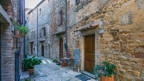 Una estrecha calle adoquinada bordeada por edificios históricos de piedra con puertas y contraventanas de madera.