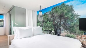 Un dormitorio con una cama grande, una puerta corrediza de vidrio y un mural de un árbol y paisaje.
