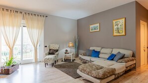 Un salon avec un canapé, un fauteuil et une petite table sur laquelle se trouve une lampe. Deux tableaux encadrés sont accrochés au mur.