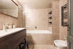 A modern bathroom with a bathtub, a vanity with a mirror, and a sink. - Apartments Florence - Palazzo Benci with river view · Palazzo Benci with river v (Firenze)
