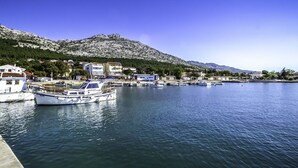 A marina with boats docked, a mountain in the background, and buildings along the shore.