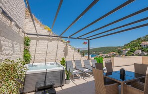 Eine Dachterrasse mit Whirlpool, Liegestühlen und einem Tisch.