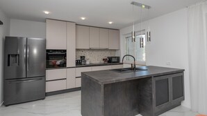 A modern kitchen with a large island, stainless steel appliances, and a minimalist design. - Awesome home in Pucisca with house sea view (Pucisca)