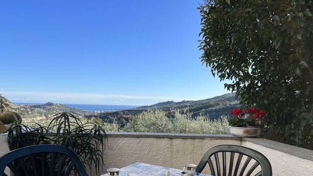Une table dressée pour le thé, avec une vue panoramique sur les collines et la mer.