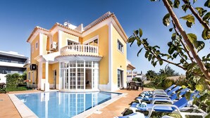Ein gelbes Gebäude mit Pool und Liegestühlen.