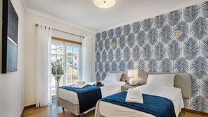 Ein Hotelzimmer mit zwei Betten, einem großen Fenster und einer Wand mit Muster.