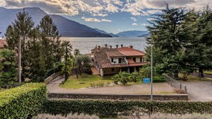 Ein Haus mit rotem Ziegeldach, umgeben von viel Grün und Blick auf einen See.