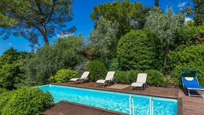 A swimming pool with wooden deck and lounge chairs, surrounded by lush greenery and trees. - Stunning private villa for 8 people with WIFI, private pool, A/C, TV, patio and panoramic view (San Casciano In Val Di Pesa)