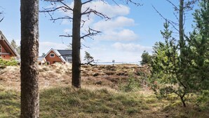 Ein Haus mit geneigtem Dach und Solaranlagen, umgeben von einer grünen Landschaft und Bäumen.