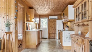 Ein Holzhütten-Innenraum mit Küchenzeile, einschließlich Schränken, einem Kühlschrank und einem Fenster.