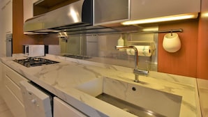 Een moderne keuken met een roestvrijstalen afzuigkap, een inbouwmagnetron en een marmeren aanrecht.