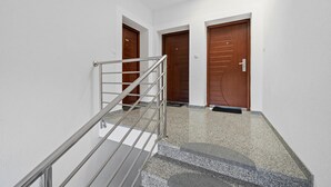 Um interior moderno com escada de metal que leva a um patamar, paredes brancas e portas de madeira.