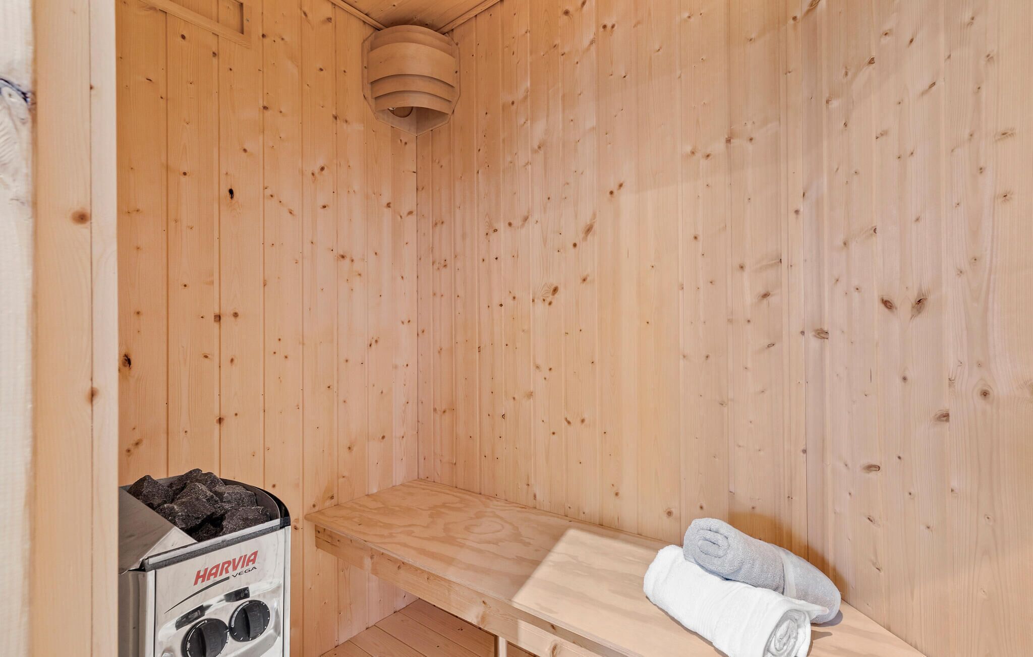 Una sauna amb parets de fusta, una banca i un escalfador de sauna anomenat 'HARVIA VEGA'.