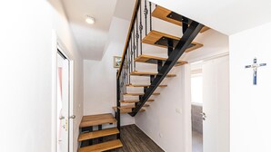 Eine Holztreppe mit schwarzen Metallgeländern und einer weißen Wand.