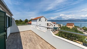 Ein Balkon mit Blick auf eine Küstenstadt, einen klaren Himmel und eine ferne Bergkette.