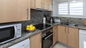 A kitchen with wooden cabinets, a granite countertop, a microwave, an oven, and a sink.