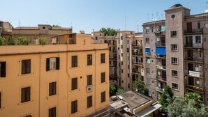 A multi-story residential building with balconies, air conditioning units, and a clear blue sky.