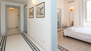 A hotel room with a bed, a bathroom with a mirror and towel, and a hallway with framed pictures.