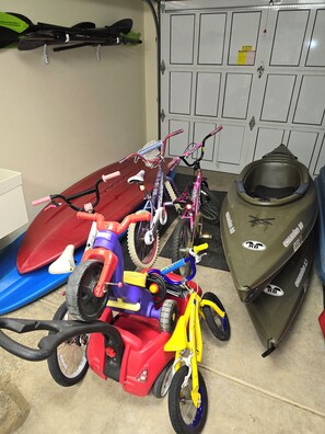 A garage with various vehicles including a red ATV, a purple bicycle, and a green snowmobile. - Water Lover's Paradise (Rockaway Beach)