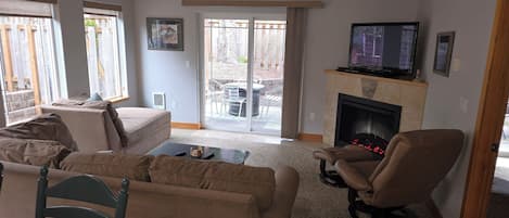 Una sala de estar con sofá, sillón, televisor y chimenea.