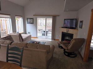 A living room with a sofa, a chair, a television, and a fireplace. - Water Lover's Paradise (Rockaway Beach)