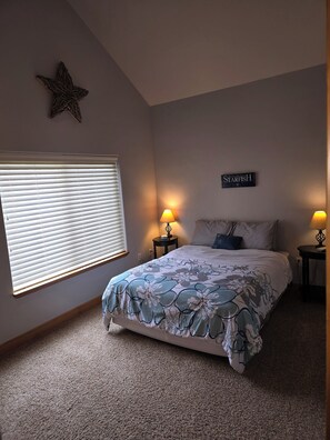 A bedroom with a bed, two bedside lamps, a star decoration, and a sign on the wall. - Water Lover's Paradise (Rockaway Beach)