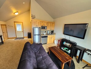 A compact living space with a kitchenette, a sofa, a TV, and a small table. - Water Lover's Paradise (Rockaway Beach)