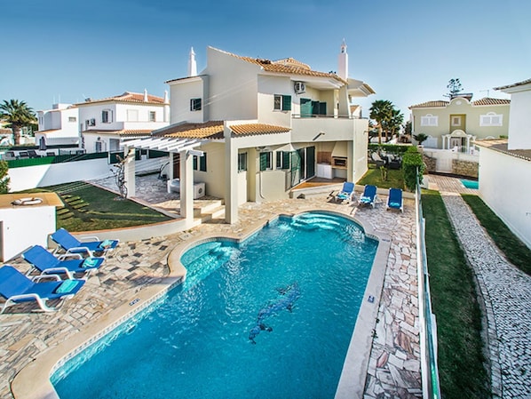 A modern villa with a swimming pool, outdoor seating, and a well-maintained garden.