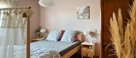 A bedroom with a bed, bedside tables, a lamp, a wall art piece, and a window with curtains.
