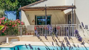 A poolside view of a house with a covered patio, a swimming pool, and surrounding lavender plants. - Beautiful home in Vias (Vias)